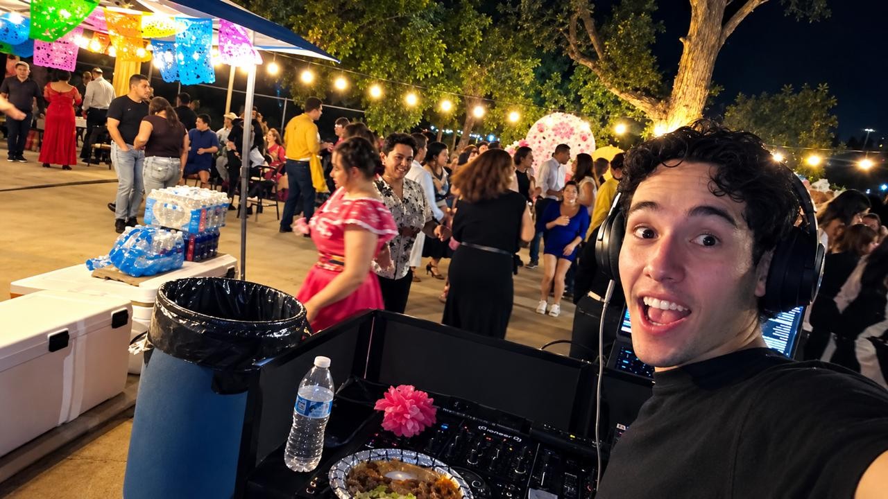 DJRinzler smiling at the decks during an outdoor evening party