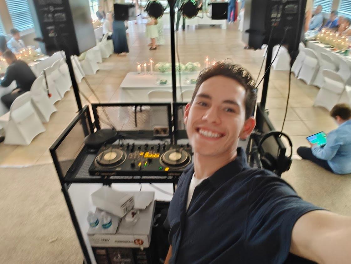 DJRinzler smiling beside his DJ setup